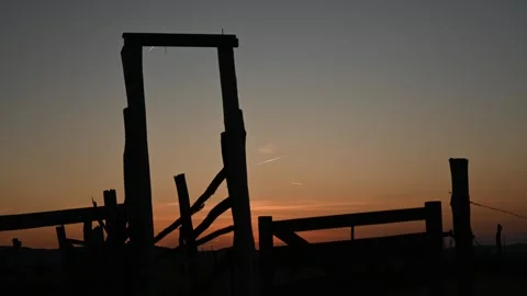 A post sunset time lapse of a bright orange sky behind a dilapidated corral Stock Footage 251485466