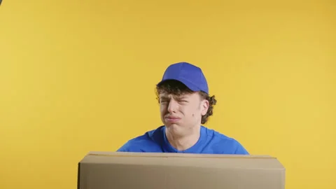 Postal courier man with heavy parcel box. Postman delivers address package on Stock Footage 277507933