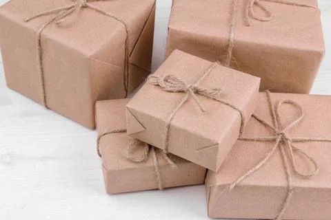 Postal parcels. boxes wrapped in craft paper on a white wooden table. mail or Stock Photos