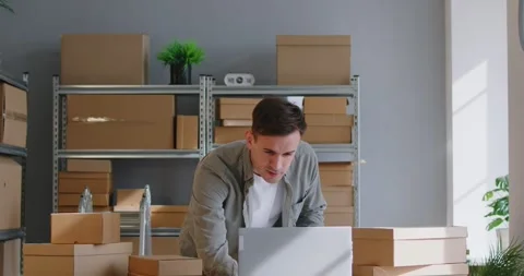 Postal warehouse person working inventory parcel boxes audits using laptop Stock Footage 285656764