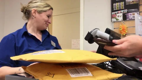 Postal Worker Accepting Payment and Scanning Packages at a Service Counter Stock Footage 342341317