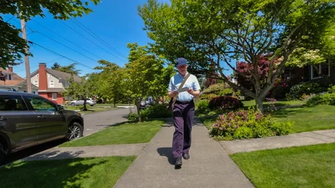 Postal worker hand delivering mail while walking down a sidewalk in a upscale ne 動画素材 154213526