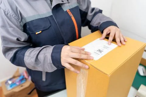 Postal workers handle parcel boxes by attaching barcode stickers. Stock Photos