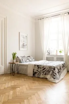 Poster above bed with patterned blanket in white hotel bedroom interior with  写真素材