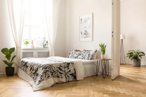 Poster above bed with patterned cushions in bright bedroom interior with wind Stock Photos