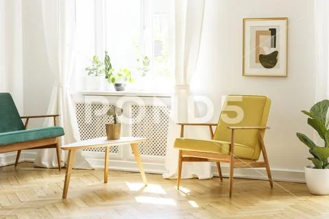 Poster above yellow wooden armchair at table in retro living room interior wi Stock-Fotos