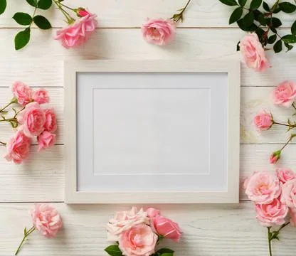 Poster frame mockup, top view, pink roses on white wooden background.Holiday con Stock Photos