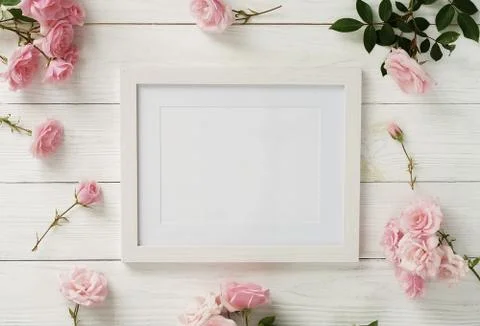 Poster frame mockup, top view, pink roses on white wooden background.Holiday con Stock Photos
