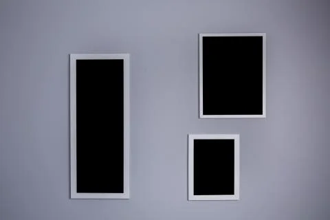 Poster mockup with three frames on empty grey wall Stock Photos