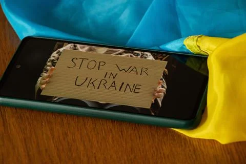 Poster with the text Stop War in Ukraine in the hands of a girl on the screen Stock Photos
