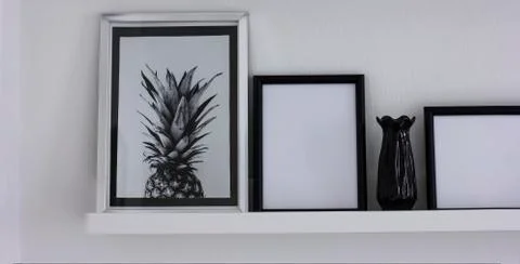 Posters with pineapple and clean frames on the shelf, modern interior in blac Stock Photos