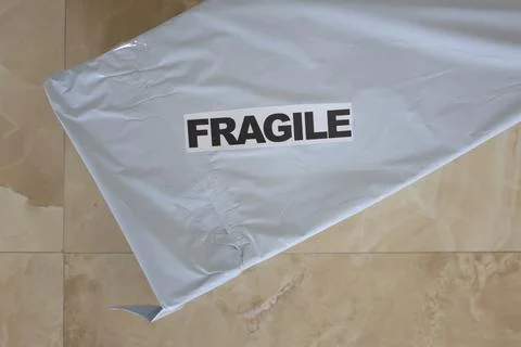 Posting package in gray plastic bag with fragile sign Photos