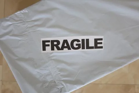 Posting package in gray plastic bag with fragile sign 写真素材