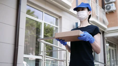 Postman, delivery man in protective mask, medical gloves carry small box parcel Stock-Footage 134394260