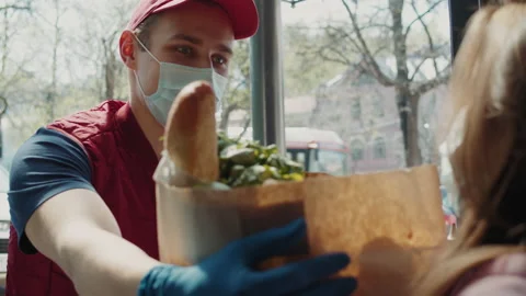 Postman or delivery man in mask during coronavirus carry small box food deliver Stock Footage 130259143