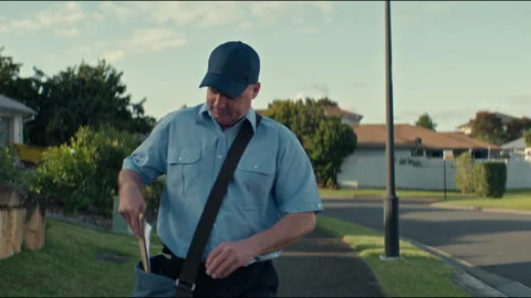 Postman with the postal bag walking towards his destination and smiling Stock Footage 263975379
