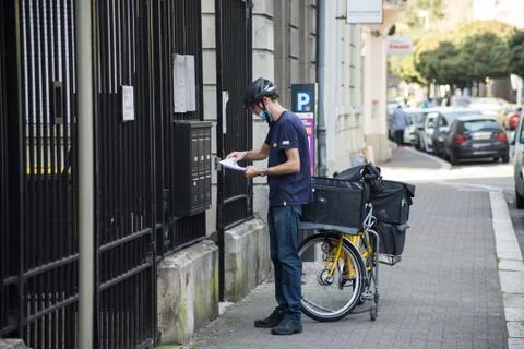 Postman putting letters in mail boxes in the street Stock Photos