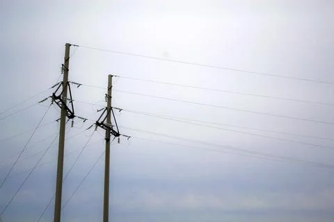 Posts with wires of high voltage on background of sky in sunlight. Monochrome Stock Photos