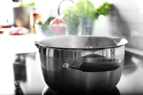 Pot with boiling water on electric stove in kitchen Stock Photos