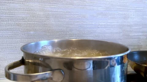 Pot of boiling water over kitchen background. Bubbles of boiling water. Slow Stock Footage 232310601
