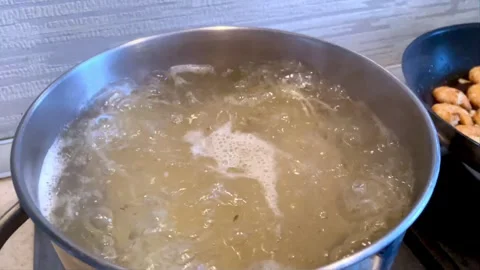 Pot of boiling water over kitchen background. Bubbles of boiling water. Slow Stock Footage 255390577