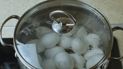 A pot of boiling water in which white chicken eggs are boiled. Water boils in a Stock Footage 240598016