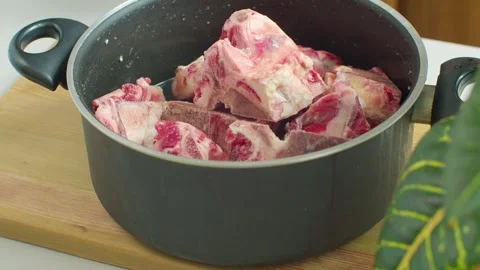A pot with bones is placed on a wooden table beside a cutting board. 動画素材 312720023