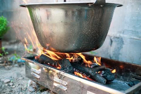 Pot cauldron over open fire, preparing stew soup on wood grill, outdoor cooki Stock Photos