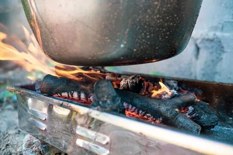 Pot cauldron over open fire, preparing stew soup on wood grill, outdoor cooki Stock Photos
