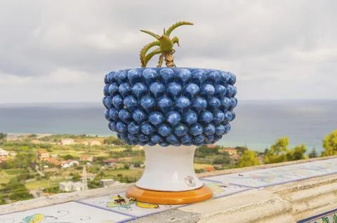 Pot of ceramic flowers in the shape of a half pinecone with a cactus in the city Stock Photos