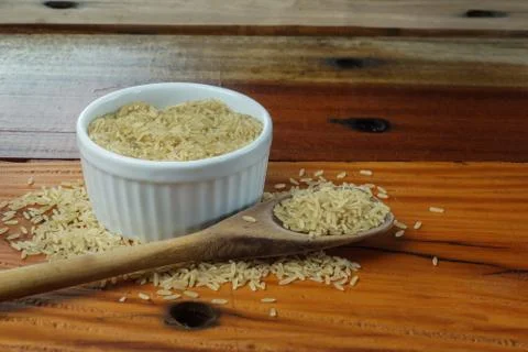 POT CONTAINING RAW INTEGRAL RICE ON A RUSTIC TABLE Stock Photos