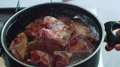 A pot filled with bones and water is placed on a stovetop. Vídeo Stock 312720030