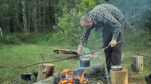 In a pot on the fire boiling water. A man removes scum and throws away Stock Footage 64447000