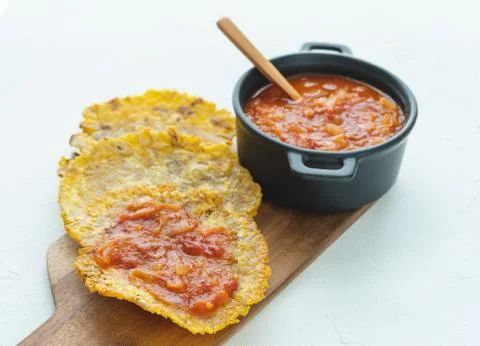 Pot with fried tomato accompanied by fried banana on a white background. Typi Stock Photos