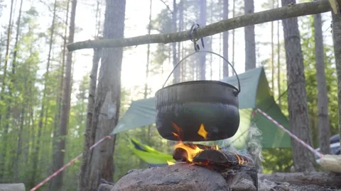 A pot hanging on a stick over the fire, the fire wrapped around it Stock Footage 131548866