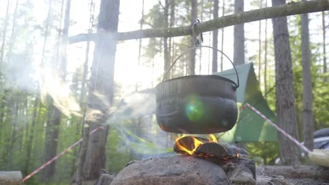 A pot hanging on a stick over the fire, the fire wrapped around it Stock Footage 131548885