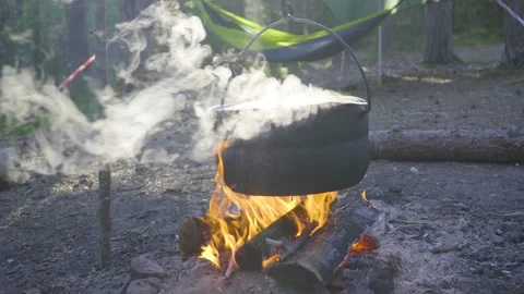 A pot hanging on a stick over the fire, the fire wrapped around it Stock Footage 131548906