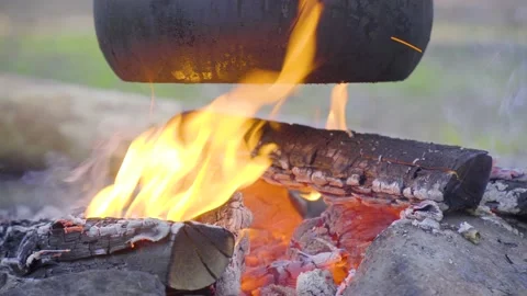 A pot hanging on a stick over the fire, the fire wrapped around it Stock Footage 131548929