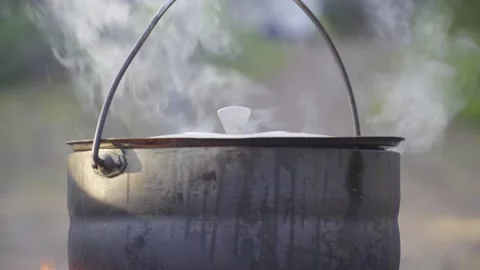 A pot hanging on a stick over the fire, the fire wrapped around it Stock Footage 131548933