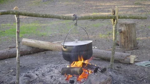 A pot hanging on a stick over the fire, the fire wrapped around it Stock Footage 131548944