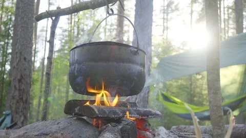 A pot hanging on a stick over the fire, the fire wrapped around it Stock Footage 131549003