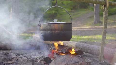 A pot hanging on a stick over the fire, the fire wrapped around it Stock Footage 131549011
