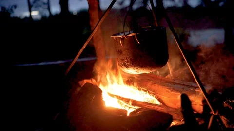 A pot hangs on a trinog on a fire, flames twine around it, there is smoke 動画素材 102055583