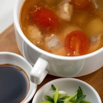 Pot of meat soup or broth with tomatoes, sauce and salad. Close up shot. Top Stock Photos