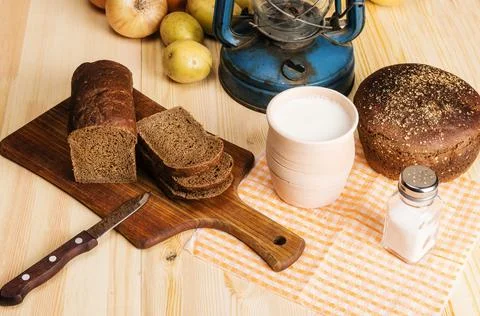 Pot of milk, rye bread, a cutting board, salt, onions, potatoes Stock Photos