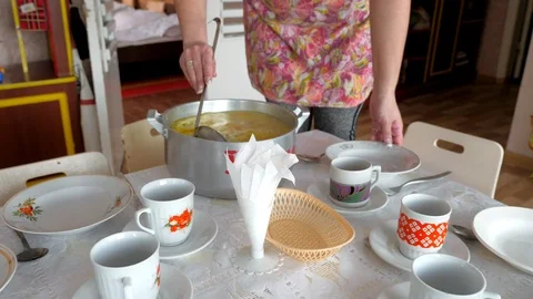 Pot of soup and hands with an empty plate and a ladle. Steel saucepan from broth Stock Footage 87043991