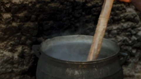 A Pot is Stirred Over an Outside Fire co Stock Footage 115736191