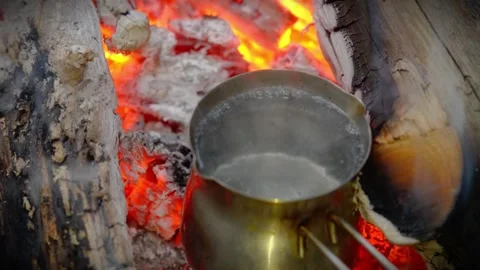 Pot of water boiling over hot campfire coals in the woods. Stock-Footage 341977841