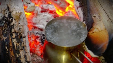 Pot of water boiling over hot campfire coals in the woods. Stock Footage 341977853