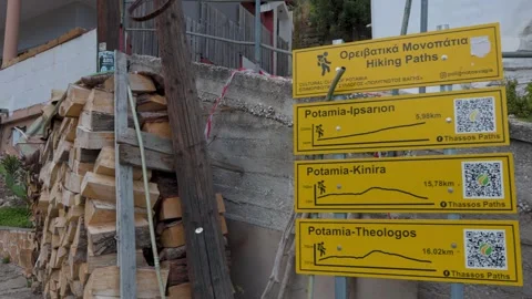 POTAMIA, THASSOS, GREECE - SEPTEMBER 15, 2025 Hiker walking past trail signs Stock Footage 341684774